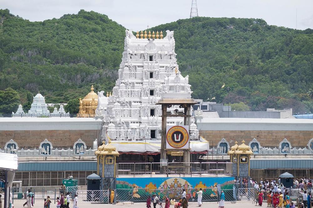 The white gopuram of the Tirumala Venkateswara temple against green hills